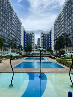 a swimming pool with umbrellas in front of some buildings at Sea Residences MOA Pasay City- Kirk in Manila