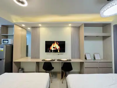 a room with two beds and a desk with a fireplace at Budget Condo near Airport and Mall of Asia in Manila
