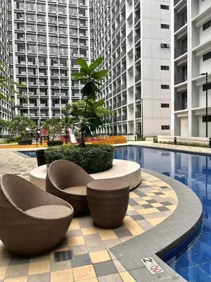 a pool with two chairs and a tree in a building at Budget Condo near Airport and Mall of Asia in Manila