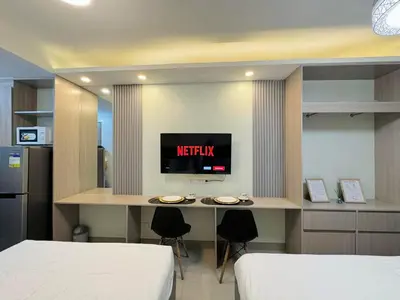 a bedroom with two beds and a desk with a tv at Budget Condo near Airport and Mall of Asia in Manila