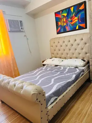 a bed in a bedroom with a painting on the wall at Tulip Garden Condominium Southwoods in Biñan