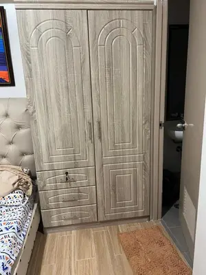 a closet with a wooden door next to a bed at Tulip Garden Condominium Southwoods in Biñan
