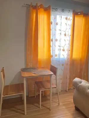 a table and a chair in a room with curtains at Tulip Garden condo in Biñan