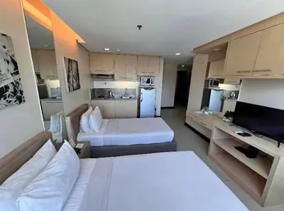 a living room with two beds and a kitchen at Spacious Cozy Corner in Manila