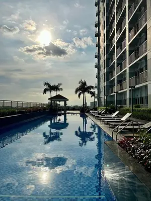 a swimming pool with palm trees and a building at Atmosphere You Secret Hideaway in Manila