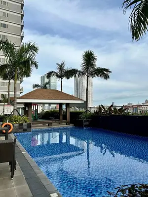 a large swimming pool with palm trees and a building at Atmosphere You Secret Hideaway in Manila