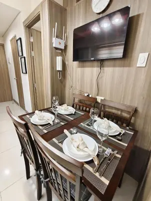 a dining room table with chairs and a television on the wall at Escape To Paradise in Manila
