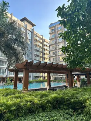 a wooden bench in a park with buildings in the background at We Vibe, 81 Newport Blvd across NAIA 3 in Manila
