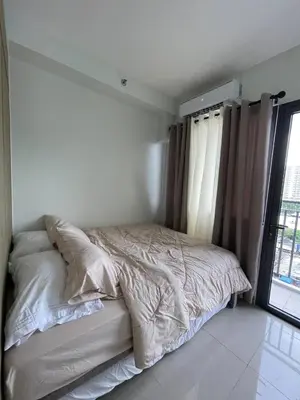 a bed in a white bedroom with a window at Apartment in Pasay in Manila