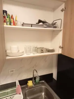 a kitchen with a sink and a shelf with dishes at Jasmine Haven in Shore2 Residences in Manila