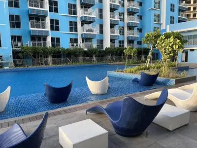 a swimming pool with blue chairs and tables and buildings at Bayshore 2 Okada Bayview WiFi Big TV Netflix Near NAIA&MOA in Manila