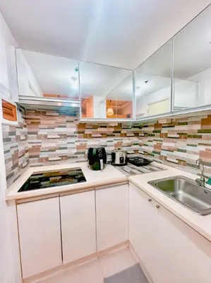 a kitchen with white cabinets and a sink at Aeva's Cozy Stay in Manila