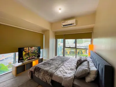a bedroom with a large bed and a flat screen tv at Exquisite 2BR Corner Suite with Sunset, Okada View in Manila