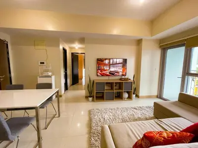 a living room with a couch and a tv on the wall at Exquisite 2BR Corner Suite with Sunset, Okada View in Manila