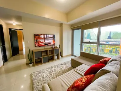 a living room with a couch and a flat screen tv at Exquisite 2BR Corner Suite with Sunset, Okada View in Manila
