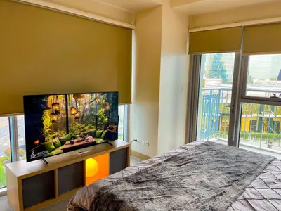 a bedroom with a flat screen tv and a large window at Exquisite 2BR Corner Suite with Sunset, Okada View in Manila