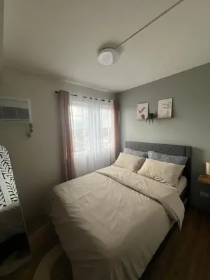a bedroom with a bed with white sheets and a window at Ananda Square in Manila