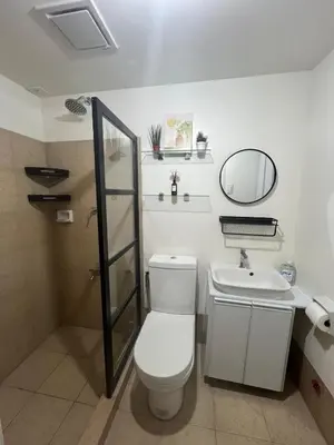 a bathroom with a toilet and a sink and a mirror at Ananda Square in Manila