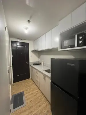 a kitchen with white cabinets and a black refrigerator at Ananda Square in Manila