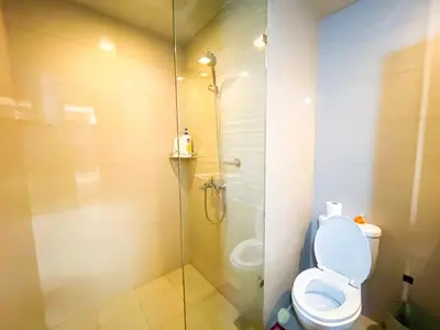 a bathroom with a toilet and a glass shower at Bayshore Resort Residences - Okada Manila in Manila