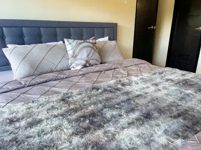 a bed with a blanket and pillows on it at Bayshore Resort Residences - Okada Manila in Manila