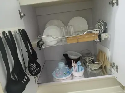 a shelf with plates and utensils in a kitchen at Condo sa south residences tower 3 in Manila