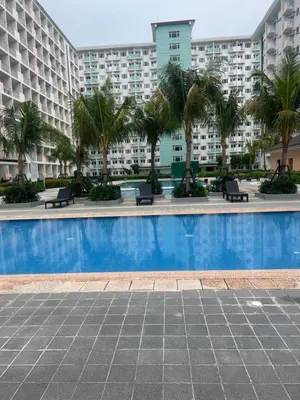 a swimming pool with palm trees and buildings at King Elite Condo Hotel Field Residences Near NAIA Airport in Manila