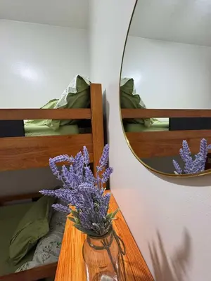 a vase with purple flowers on a table with a mirror at R & A Enclave in Manila