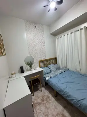 a bedroom with a bed and a desk with a ceiling fan at R & A Enclave in Manila