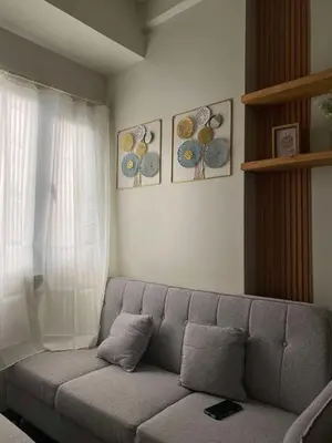 a living room with a gray couch in front of a window at R & A Enclave in Manila
