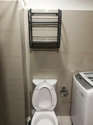 a bathroom with a toilet and a shelf above it at Cozy Home near Mall of Asia with WIFI and Netflix in Manila