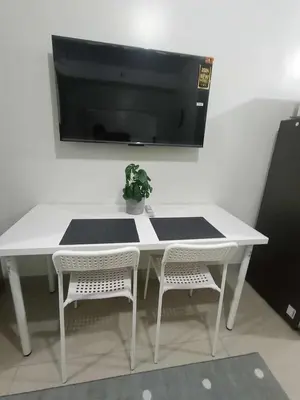 a white table with two chairs and a tv on the wall at Cozy Home near Mall of Asia with WIFI and Netflix in Manila