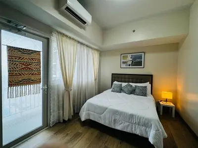 a bedroom with a bed and a large window at 7FF Cozy 1BR Park McKinley West near BGC & Venice Mall in Manila
