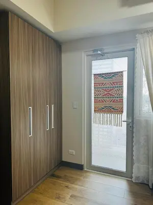 a room with a door and a window with a curtain at 7FF Cozy 1BR Park McKinley West near BGC & Venice Mall in Manila