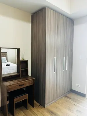 a bedroom with a large wooden cabinet and a mirror at 7FF Cozy 1BR Park McKinley West near BGC & Venice Mall in Manila
