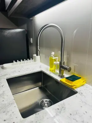 a kitchen counter with a sink with a yellow sponge at 7FF Cozy 1BR Park McKinley West near BGC & Venice Mall in Manila