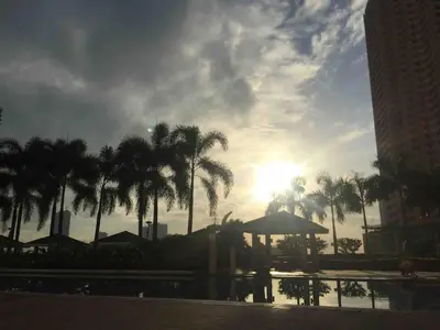 a sunset over a pool with palm trees and the sun at Casa Cashmere in Light residences at Mandaluyong City in Manila