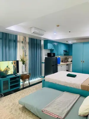 a bedroom with two beds and a kitchen with blue cabinets at Baywtach 1503 in Manila