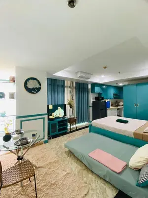 a bedroom with a large bed and a living room at Baywtach 1503 in Manila