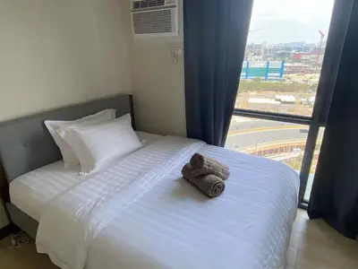 a bed with towels on it with a large window at 1BR 2 mins to Okada near MOA & Airport-12C in Manila