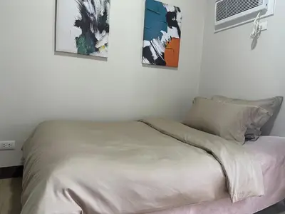 a bed in a bedroom with two pictures on the wall at 1BR 2 mins to Okada near MOA & Airport-12C in Manila