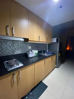 a kitchen with wooden cabinets and a sink and a refrigerator at Great Price and Location in Moa, Pasay City, Philippines in Manila
