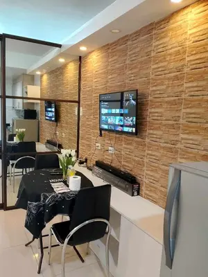 a dining room with a tv on a brick wall at Affordable unit near MOA walking distance to picc in Manila