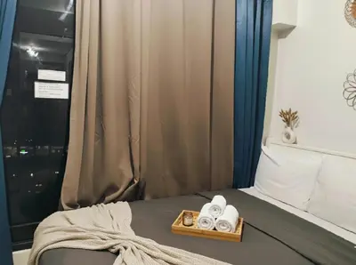 a bed with a tray of towels and a window at Mall of Asia - Aseana Residences SHORE APARTMENTS in Manila