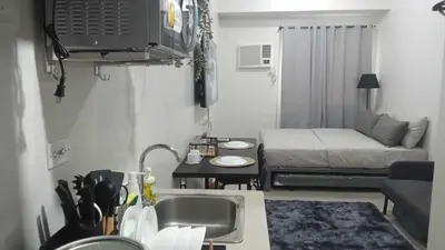 a small kitchen with a sink and a living room at 2019 Cavite Green 2 Condo Amenities HI Speed Wifi in Dasmariñas