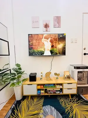 a living room with a tv on a wall at 2 Bedroom and Bathroom Staycation Condo in Mandaluyong City near BONI MRT with WIFI and KARAOKE and POOL in Manila