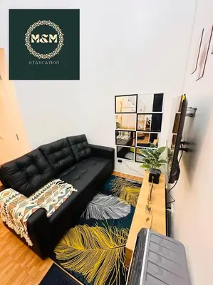a living room with a black couch on a rug at 2 Bedroom and Bathroom Staycation Condo in Mandaluyong City near BONI MRT with WIFI and KARAOKE and POOL in Manila