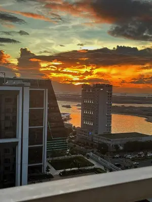 a view of a city with a sunset in the background at Manila Bay, Seaside living near MOA, Studio unit in Manila