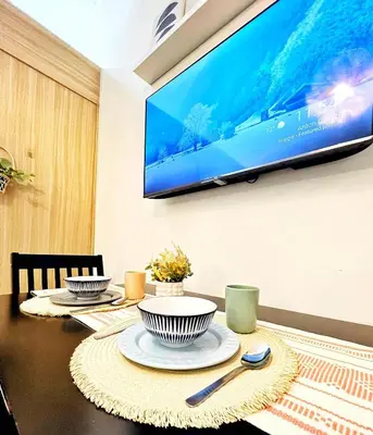 a dining room table with a television on a wall at Manila Bay, Seaside living near MOA, Studio unit in Manila