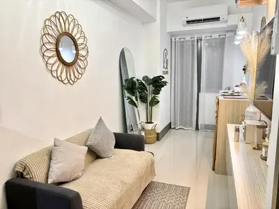 a living room with a couch and a mirror at Cozy and Stylish Unit in Fame Residences in Manila